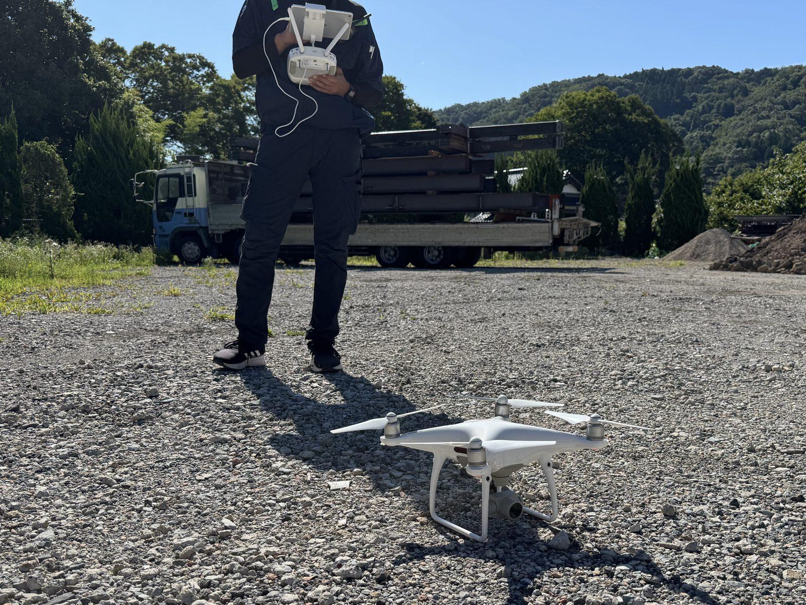屋外の広い敷地で、大型のドローンを操縦する様子